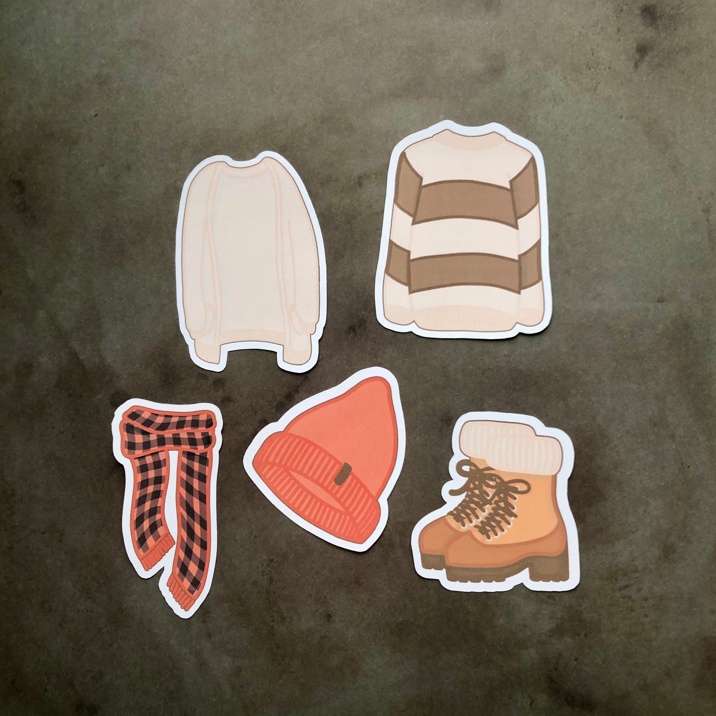 A set of five autumn-themed clothing stickers, including a sweater, as cardigan, a checkered red and black scarf, a set of boots, and a red knit beanie hat.