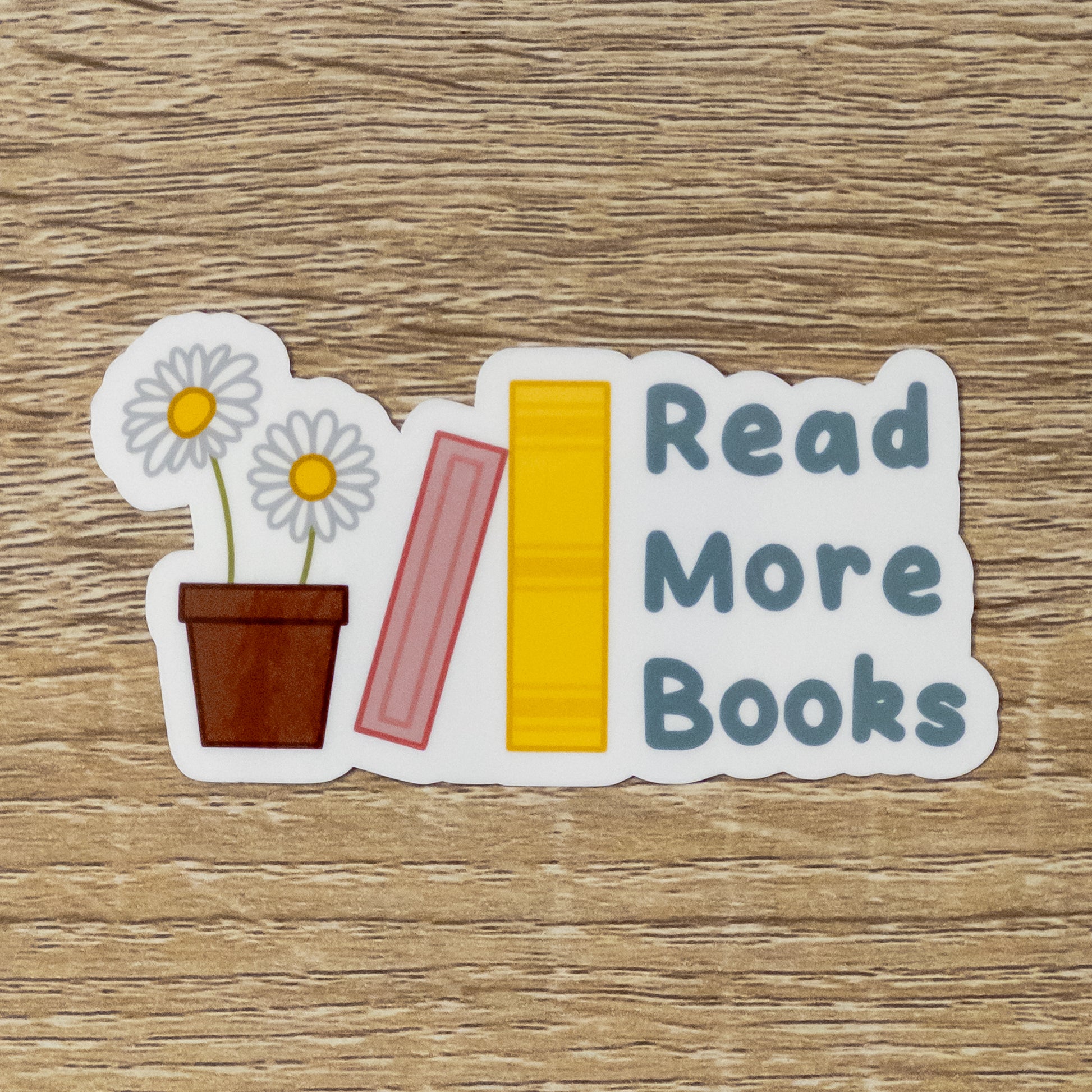 Glossy 3.4 inch tall sticker. Design is two daisies in a pot, a pink book leaning against a yellow book, and blue text that says, "Read More Books"