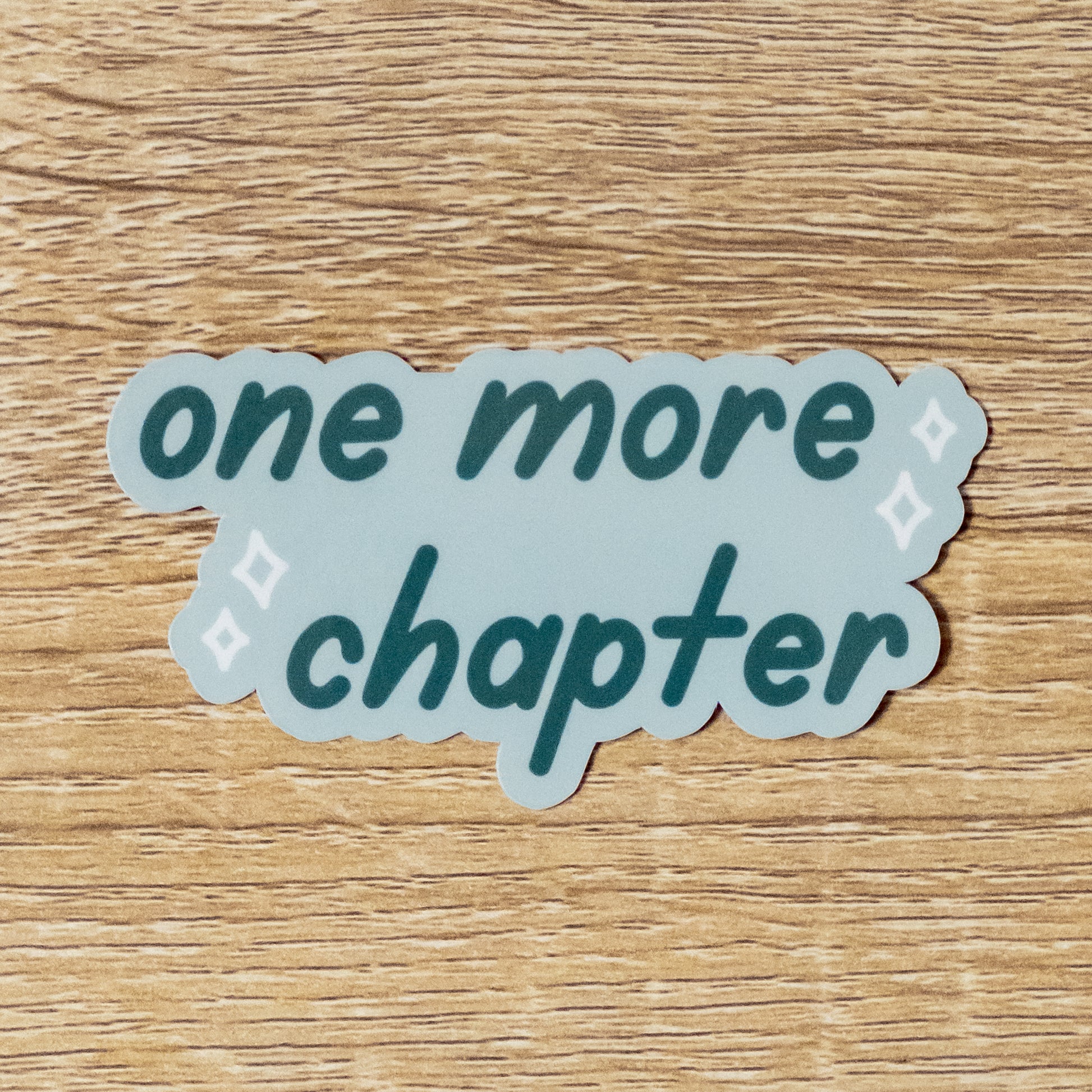 Glossy 3.3 inch wide sticker. Design is a pale blue background with light blue sparkles, and dark blue text that says, "One More Chapter"