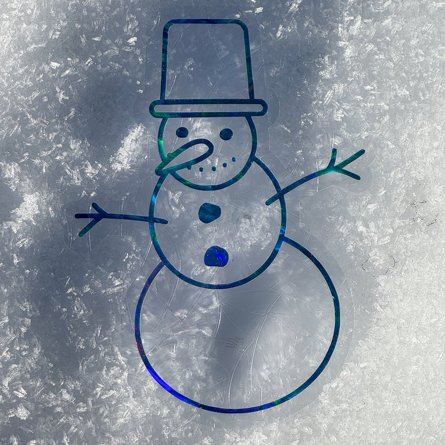 Holographic cozy winter snowman suncatcher cling decal sticker. Snowman has a carrot nose and top hat. Resting on snow.